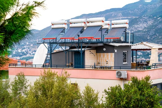 Solar panels heat water in barrels installed on roof of residential house, concept of eco-friendly energy.