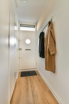 a hallway with wooden flooring and coat rack on the left side of the room, there is an open door