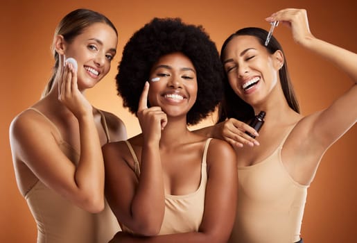 Skincare, beauty and women with product for face against an orange studio background. Portrait of a model group with oil, cream and cotton pad for skin health, wellness and care of body together.