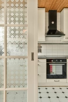 a kitchen with white cabinets and black countertops on the wall, as seen through an open glass door that leads to a stove