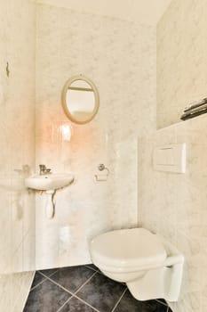 a bathroom with a toilet, sink and mirror on the wall next to it is a tiled floor that looks like marble