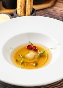 Ravioli consomme on a white porcelain plate. Healthy eating concept