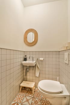 a bathroom with a toilet, sink and mirror on the wall behind it is a tiled floor that has an orange flower pattern