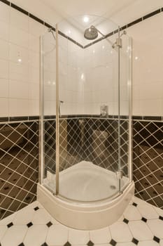 a bathroom with black and white tiles on the walls, shower stall and toilet in the floor is made out of marble