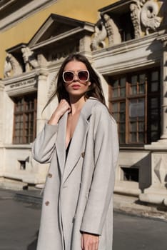 Street style, autumn, spring fashion concept: fashionable woman wearing luxury beige coat, a top with razors and sunglasses