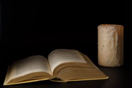 large book illuminated by the light of a white candle