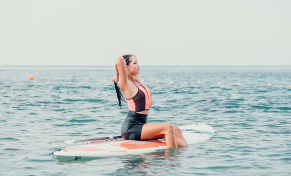 Silhouette of woman standing, surfing on SUP board, confident paddling through water surface. Idyllic sunset or sunrise. Sports active lifestyle at sea or river.