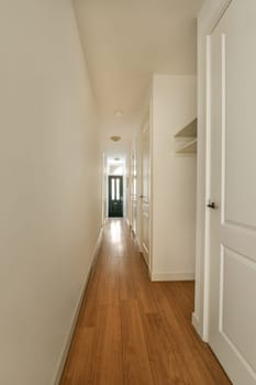 a long hallway with wood floors and white walls in an apartment building, taken from the front door to the left