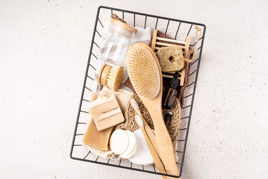 Basket with Natural bathroom and home spa tools. Zero waste concept. Bamboo toothbrush, natural soap bar, cotton pads, brush, homemade beauty products in reusable bottles on concrete background.
