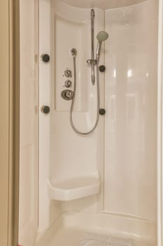 a bathroom with a shower head and hand held in the corner of the bathtub that is attached to the wall