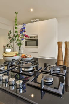 a kitchen with pots and pans on the stove top, in front of an open white cabinetd door