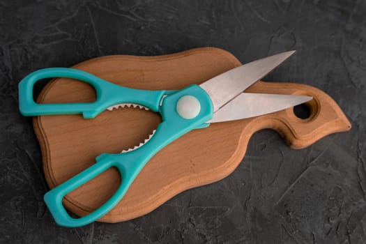 sharp kitchen scissors on a wooden cutting board in the kitchen. Close-up of kitchen accessories. cooking. Healthy eating. The cook's job. top view