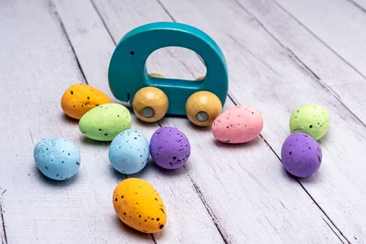 Colorful Easter eggs and children's wooden toy gift on a light background. Easter greeting card. Easter. Quail eggs. Spring holiday concept