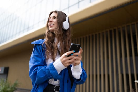 pretty young woman student relaxing outdoors in the city wearing headphones.