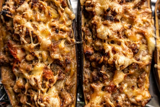 eggplant baked with meat on a baking sheet. view from above. close-up. Eggplant halves stuffed with minced meat, spices and cheese, for baking in the oven. Delicious and healthy food.