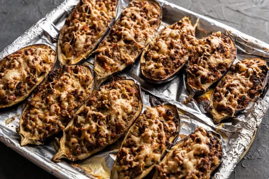 eggplant baked with meat on a baking sheet. view from above. close-up. Eggplant halves stuffed with minced meat, spices and cheese, for baking in the oven. Delicious and healthy food.