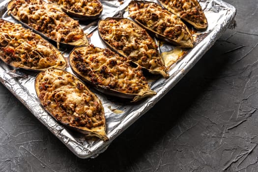 eggplant halves baked with meat on a baking sheet. view from above. Eggplant halves stuffed with minced meat, spices and cheese, for baking in the oven. Delicious and healthy food. copy space