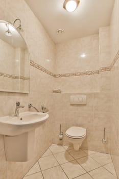 a bathroom with tiled walls and white tiles on the floor, there is a toilet in the corner next to the sink