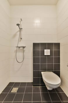 a modern bathroom with black and white tiles on the floor, shower head, and toilet seat in the corner