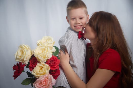 Woman with boy with flower. Mom with son on a white background in mothers Day. Family portrait with mother and boy having fun together