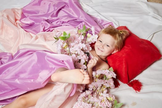 Portrait of cute kid girl posing in pink beautiful dress on white background. Young female model looking as magic princess from fairy taly