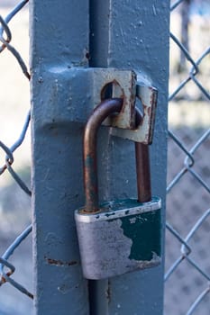 Large old padlock on a door in a metal fence