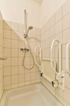 a shower stall in a public restroom with white walls and beige tiles on the wall, there is a hand rail attached to the