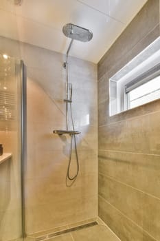 a shower room with tile flooring and beige colored tiles on the walls there is a window in the background