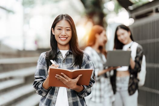 Young Asian woman college student with friends at outdoors. College student working on the college campus, education, school, study.