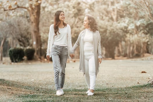 Close up of Adult daughter holding her elderly mother hand with love and walk together.