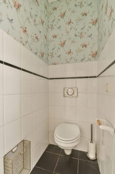 a bathroom with floral wallpaper on the ceiling and toilet in the room is white, black and tan tiles