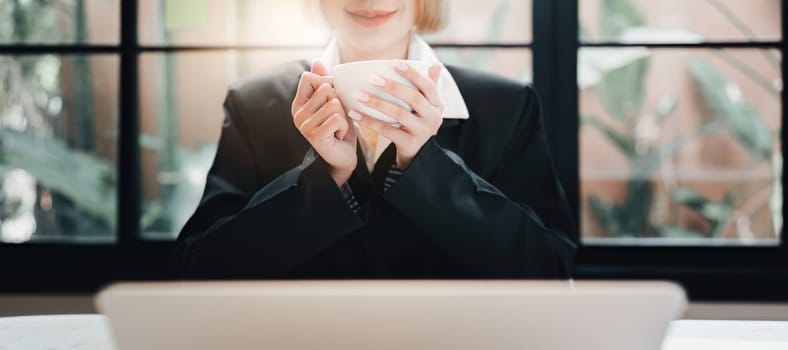 Business woman relaxing and holding hot drink and smiling at office.