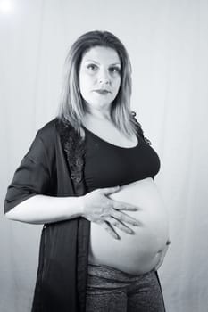 Eight months pregnant woman posing in black clothes. White background