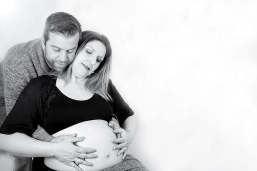 Eight months pregnant woman and dad hugging her. Happy expression