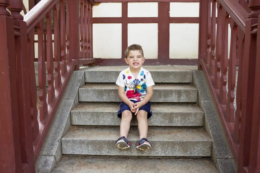 Four year old boy sitting gesturing. Alone