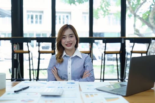 Portrait of a woman business owner showing a happy smiling face as he has successfully invested her business using computers and financial budget documents at work.