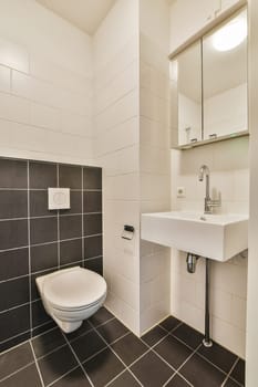 a bathroom with black and white tiles on the walls, sink and toilet in the photo is taken to the right