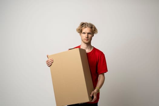Delivery guy employee man in red uniform work as dealer courier hold blank cardboard box isolated on white background studio. Delivery service concept