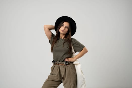 Young woman in a green t-shirt and black hat with white cotton bag