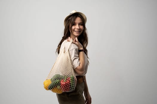 Young woman holding mesh grocery bag with vegetables Concept of no plastic. Zero waste, plastic free. Eco friendly concept. Sustainable lifestyle