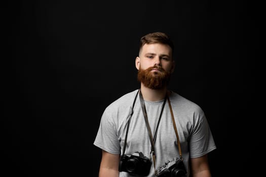 Film photography. Bearded photographer with a bunch of different vintage old film cameras. Close up portrait of man holding vintage camera