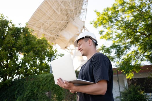 Engineer testing earth based astronomical radio telescope use laptop. Radio telescopes used in science for space observation and distant objects exploring. Big satellite dishes