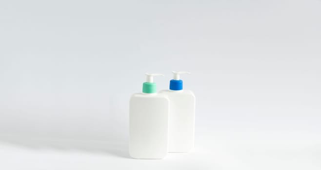 Two white unbranded bottles with a black dispenser isolated on white background. Cosmetic bottle for a cream, shampoo, oil, gel, soap, balsam