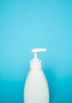 White unbranded bottle with a dispenser isolated on blue background. cosmetic packaging mockup with copy space. Bottle for a shower, gel, soap.