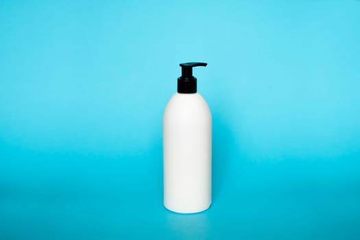 White bottle with a black dispenser for liquid soap, shampoo, gel on blue background