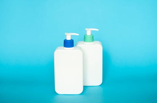 White unbranded bottles with a dispenser isolated on blue background. cosmetic packaging mockup with copy space. Bottle for a shower, gel, soap