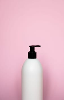 White bottle with a black dispenser for liquid soap, shampoo, gel on pink background