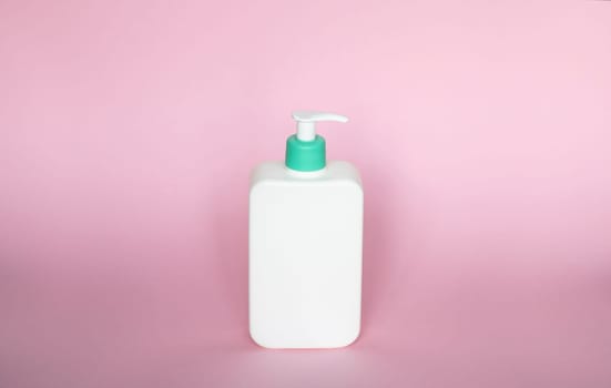 White unbranded bottle with a dispenser isolated on pink background. cosmetic packaging mockup with copy space. Bottle for a shower, gel, soap