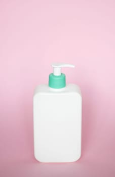 White square bottle with a cyan dispenser for liquid soap, shampoo, gel on pink background