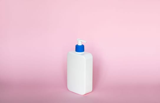 White unbranded bottle with a dispenser isolated on pink background. cosmetic packaging mockup with copy space. Bottle for a shower, gel, soap